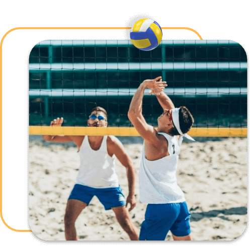Dois jogadores de vôlei em quadra de areia.