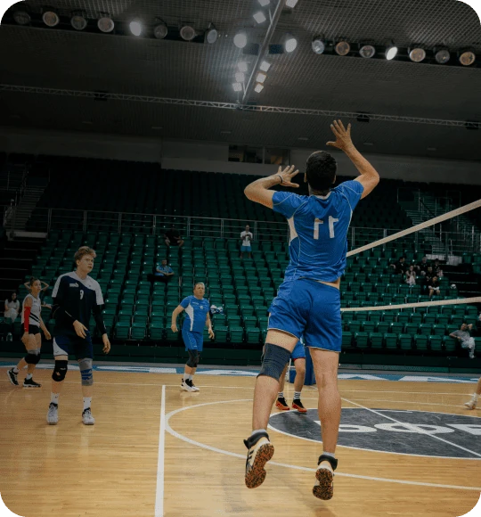 Atleta sacando em uma partida de vôlei em quadra coberta