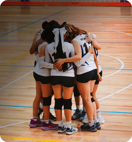 Equipe de vôlei reunida em roda no centro da quadra